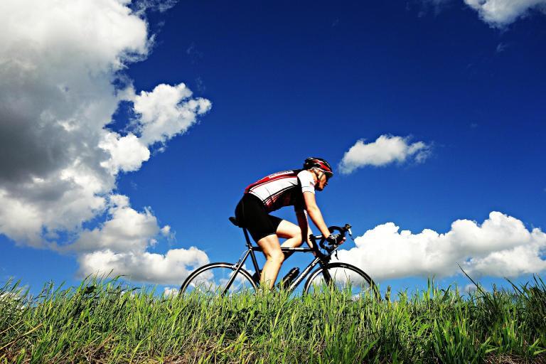 A Person Riding A Bicycle In A Grassy Area
